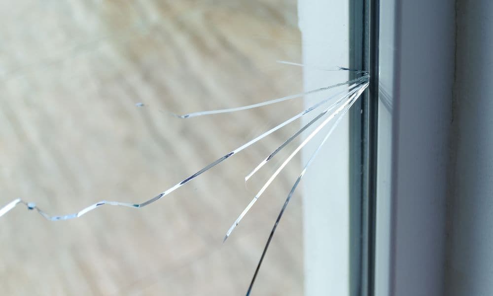 Close-up van een thermische breuk in dubbel glas met barsten in de ruit
