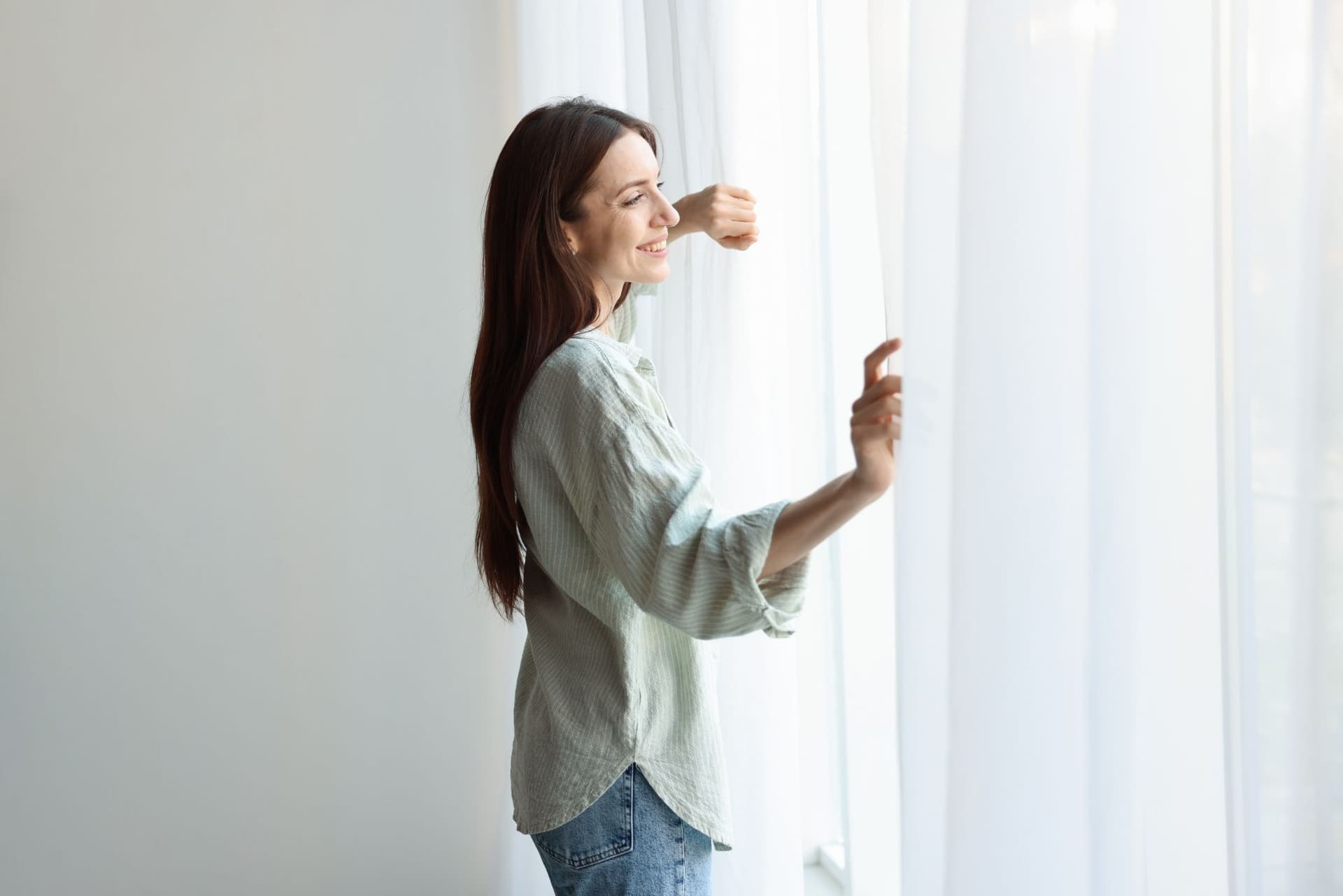 Vrouw die door gordijnen kijkt