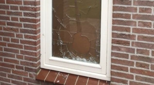 Beschadigde opening afgedicht met een houten noodvoorziening na glasschade.