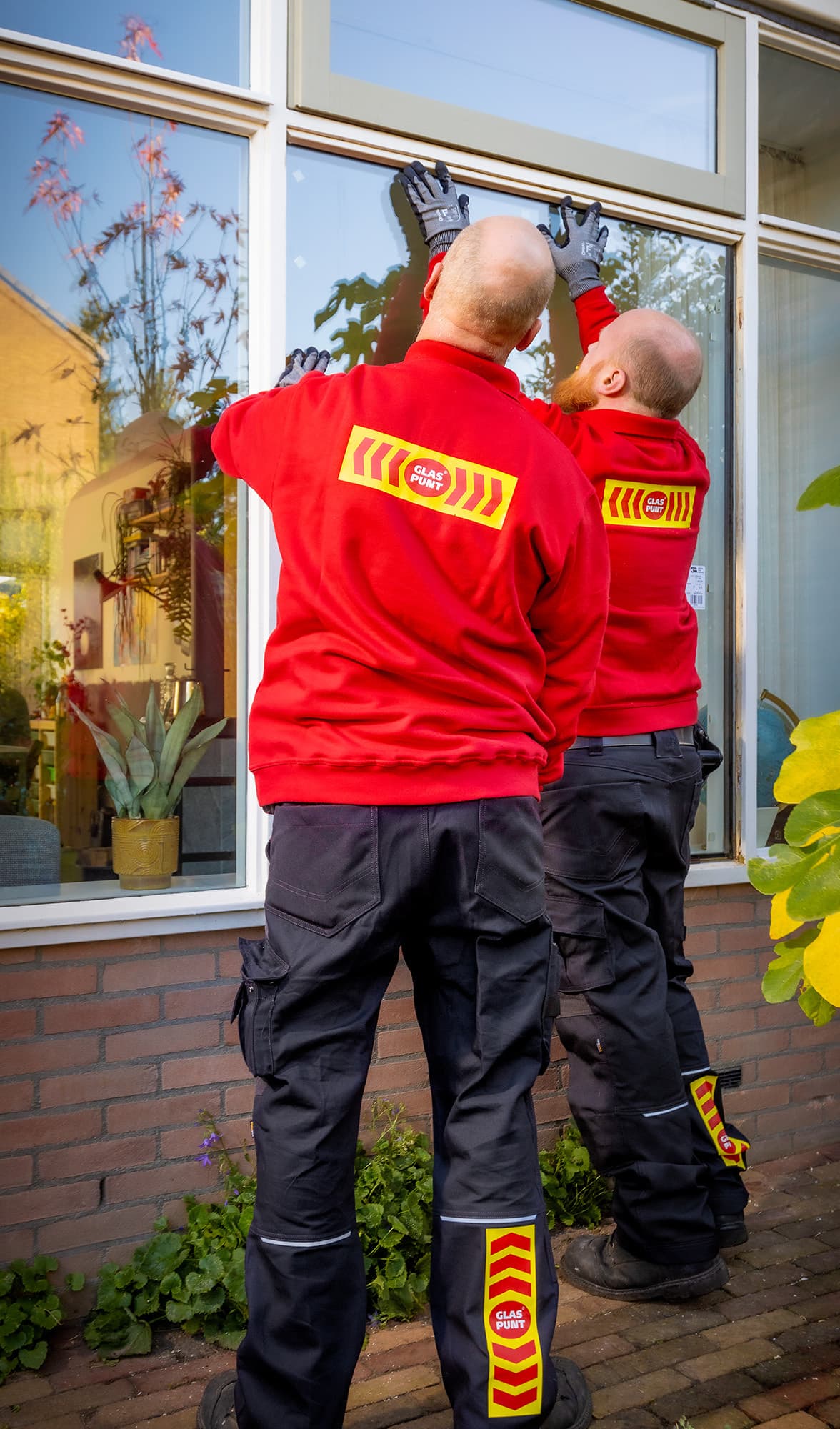 Twee glaszetters plaatsen glas in kozijn.